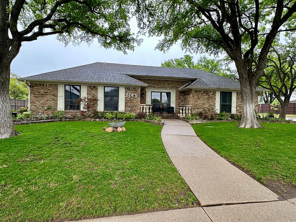 Single story home featuring brick siding, a shingled roof, and a nice front yard