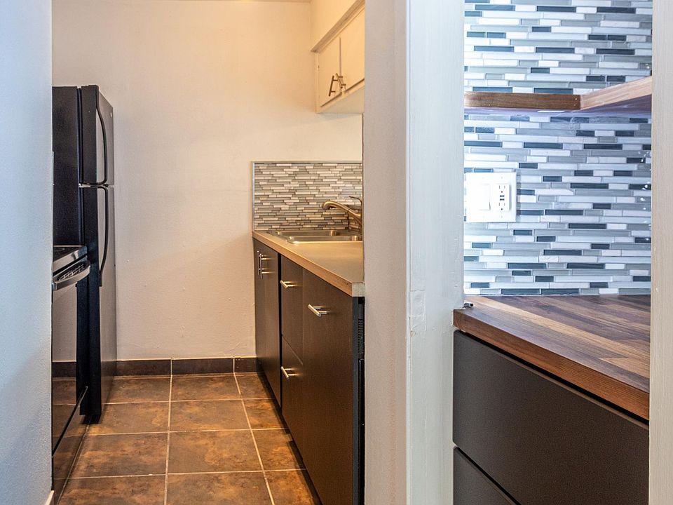 Galley kitchen with dark cabinets and tile floor. Special nook for storage or coffee bar