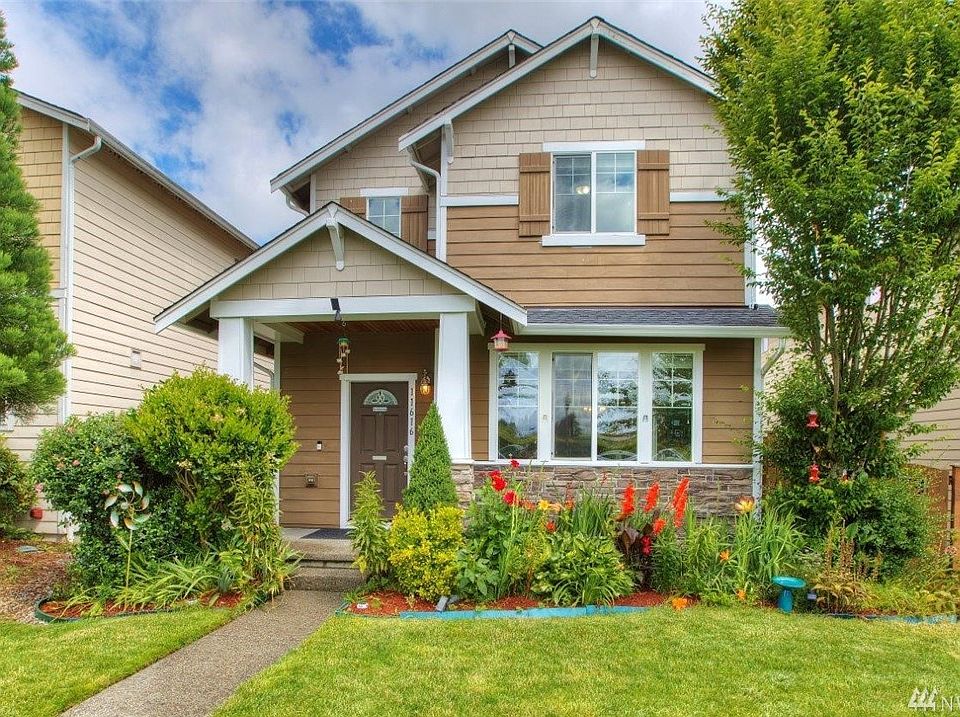 Craftsman style home with covered porch, flower garden and nice brick work on the front. 