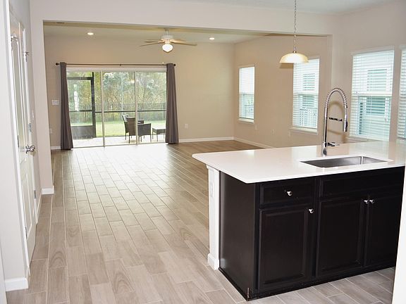 Kitchen island with quartz countertop, ceramic floors, breakfast area, family room, recessed lighting.