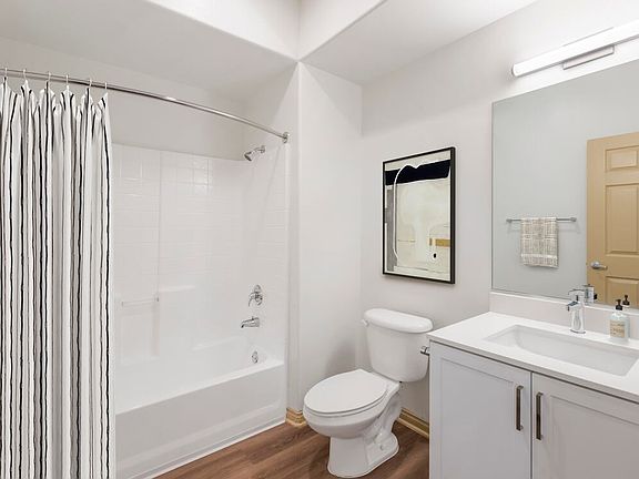 Renovated Package I bath with white speckled quartz countertop, white cabinetry, and hard surface flooring