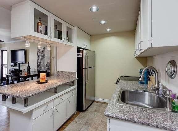 Updated kitchen with granite countertops, stainless steel sink, stove, and refrigerator