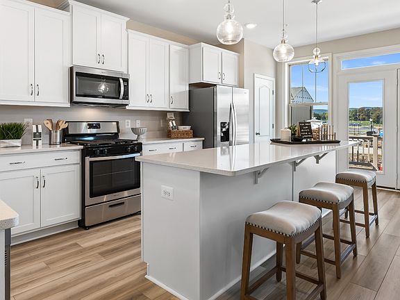 Island kitchen with white cabinets at a DRB Homes Upton II model home at the Canterbury Station comm