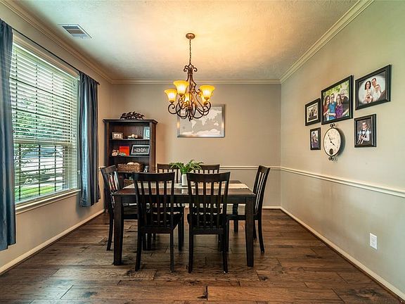 The formal dining room offers crown molding, chair rail, wrought iron chandelier and the continuation of the beautiful wood floors.