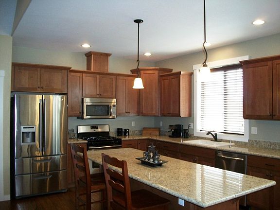 Large great room w/tall vaulted ceilings, stone wrapped fireplace w/optional niche above; model home picture - buyer may be able to choose eng floor shade/color