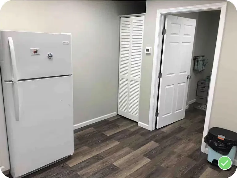 Kitchen area with full-size refrigerator and durable wood-look flooring, plus a nearby closet for extra storage.