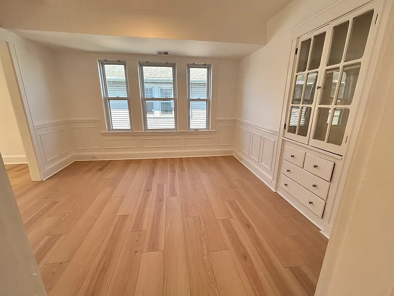Separate bright dining room with built-in china cabinet opens to sunny living room