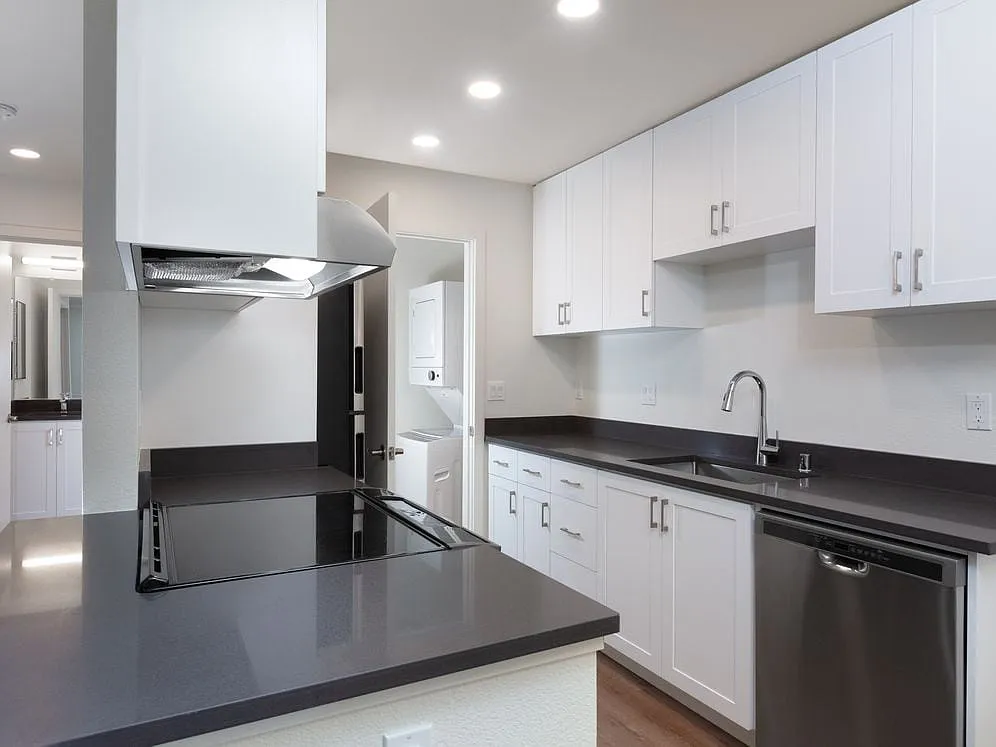 Kitchen with white cabinetry, stainless steel appliances, dark grey countertops and hard surface flooring - eaves Fremont