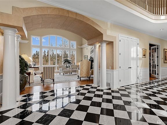 Enter the grand formal 2 story living room flanked with columns and hand painted stone work with a wall of 2 story windows framing the lake. 