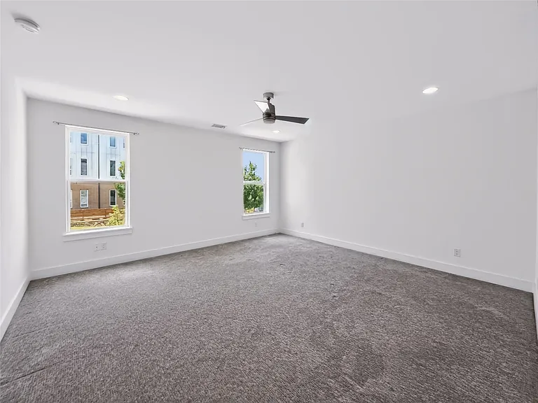 Spacious room featuring neutral carpeting, recessed lighting, and a modern ceiling fan
