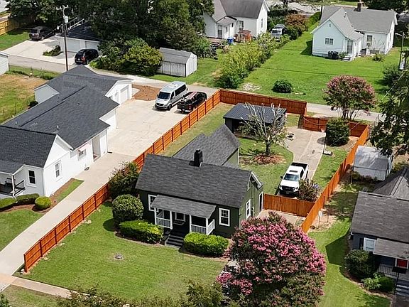 Fenced in backyard and outdoor building including enclosed storage and covered picnic space for relaxation.