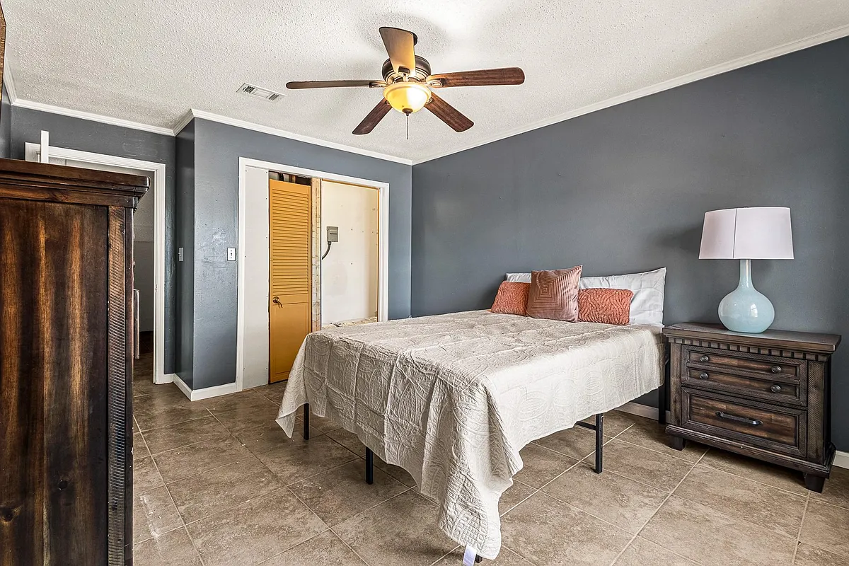 Spacious bedroom with tile flooring, ceiling fan, and room for a full bed setup plus dresser storage. - Jonesboro Rd