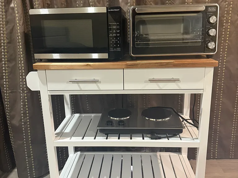 Movable cooking station which includes a microwave, toaster, oven that includes an air fryer, and two-burner stove.