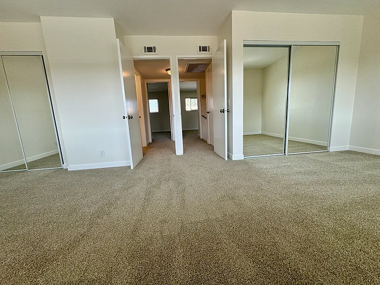 Spacious master bedroom (2 bedrooms converted to 1) with new wall to wall carpet, mirrored wardrobe doors and paint!