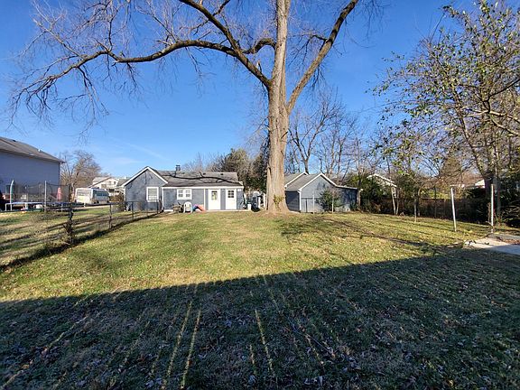 Back of home with large fenced backyard and large tree