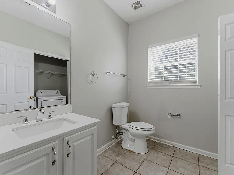 Full bath with a wide vanity, large mirror, and tiled flooring, plus a window for ventilation and natural light.