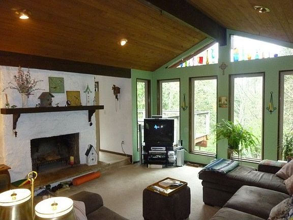 Sunken living room with vaulted ceilings and wood burning raised hearth fireplace. Floor to ceiling 