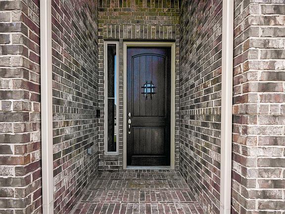 The 8' tall, royal walnut stained, mahogany door stands out among the neutral brick of the home. It's accented by the glass & grill, the Satin Nickel hardware, & the sidelight window.