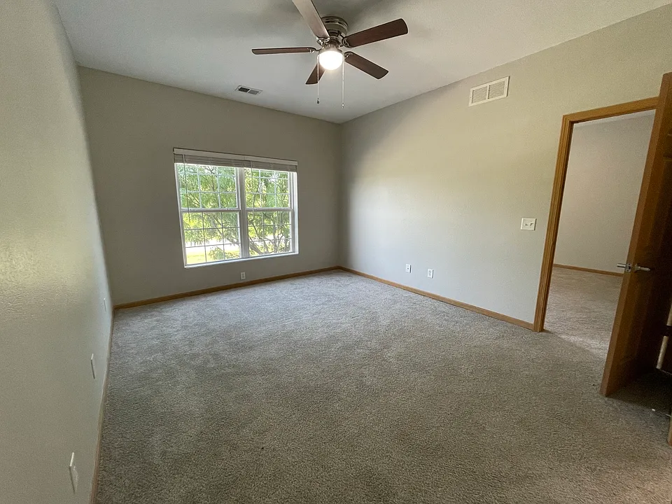 Spacious master bedroom with ceiling fan and window