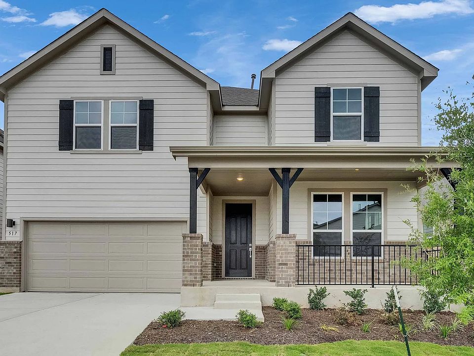 Elegant two-story home features brick accents, charming porch, and manicured lawn in Magnolia, Sprin