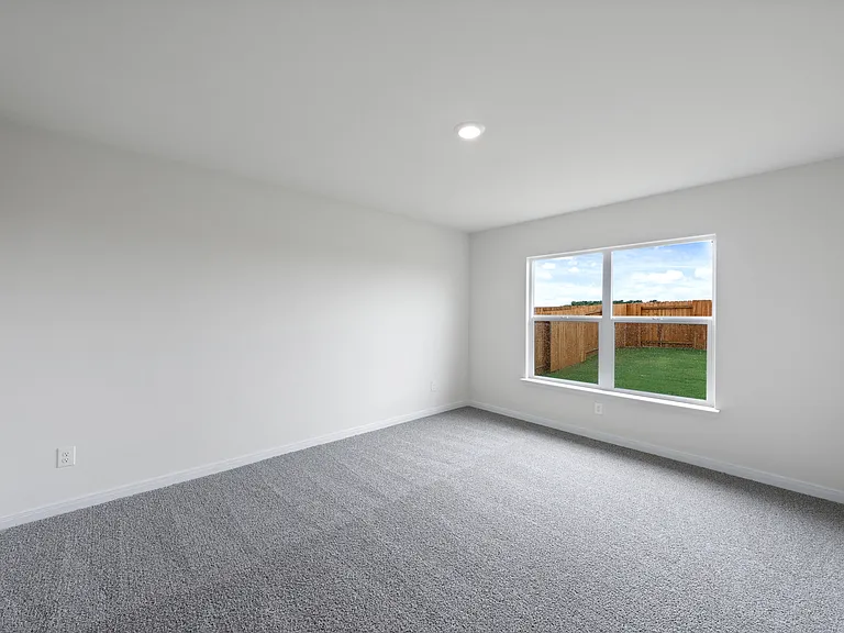 The spacious master bedroom has a large window that lets in natural light and backyard views.