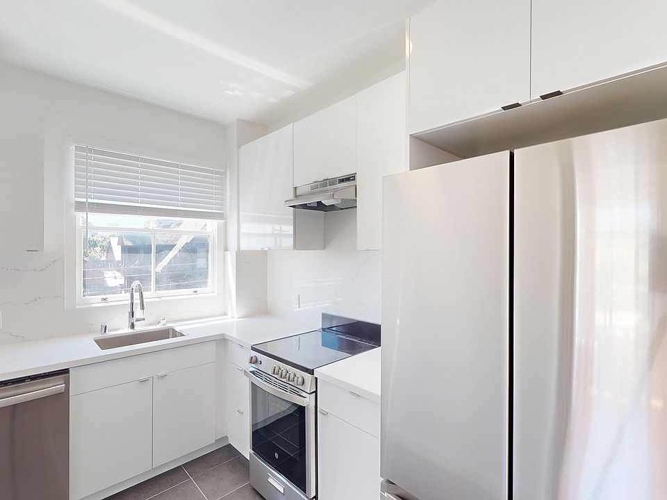 Kitchen featuring cabinetry, stainless steel appliances, a marble backsplash, and natural light from a window