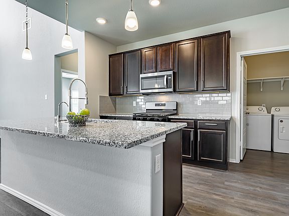 Pendant lighting, granite countertops, built-in microwave, stylish tiled backsplash, and gas cooking