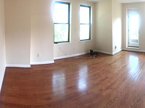 Large open living room with hardwood floors, tall ceilings.
