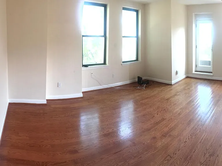 Large open living room with hardwood floors, tall ceilings.