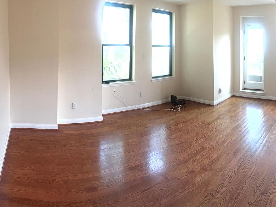 Large open living room with hardwood floors, tall ceilings.