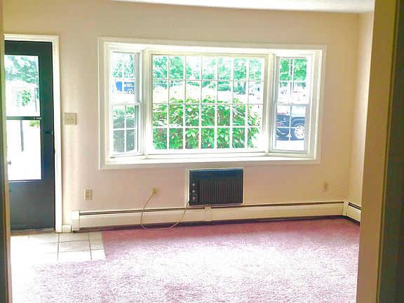 Bright Living Room looks out front. The brown wall to wall carpet In this room is used throughout the unit.