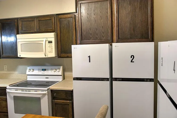 Kitchen with ample upper cabinetry, full-size range and microwave, plus individual refrigerators for each room.
