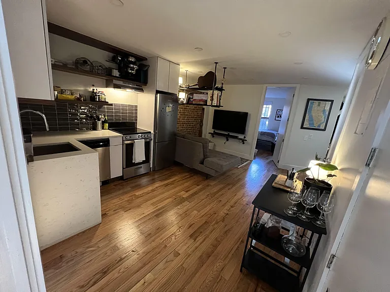 Open-concept kitchen and living area with stainless steel appliances, ample cabinetry, and hardwood floors for easy upkeep.