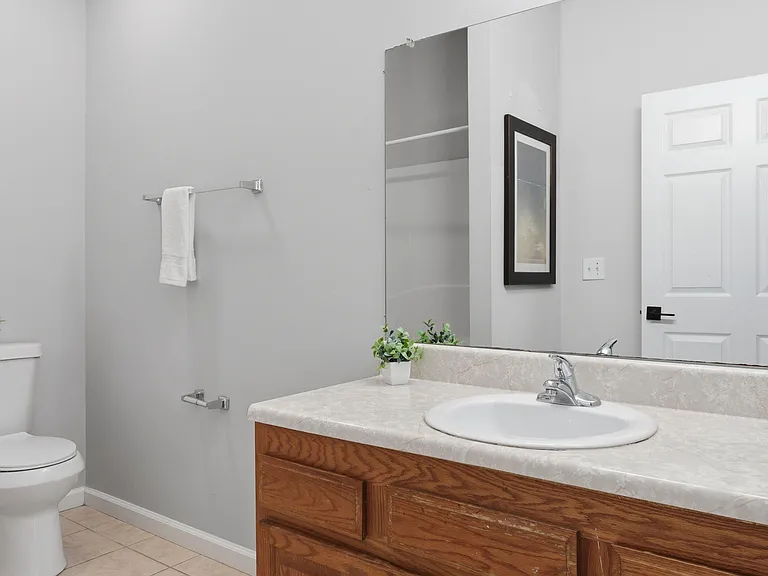 Bathroom with a wide vanity countertop, large mirror, and under-sink storage, plus convenient towel bars and tile flooring.