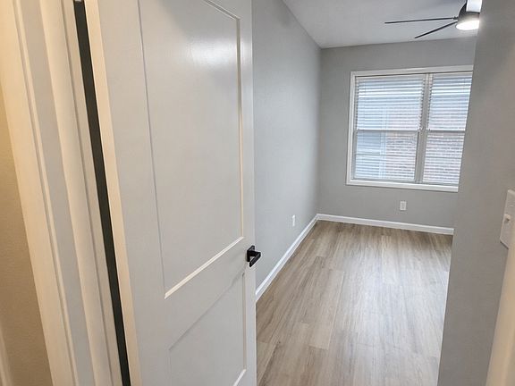 Bright bedroom featuring modern flooring, neutral paint, ceiling fan, and natural light.