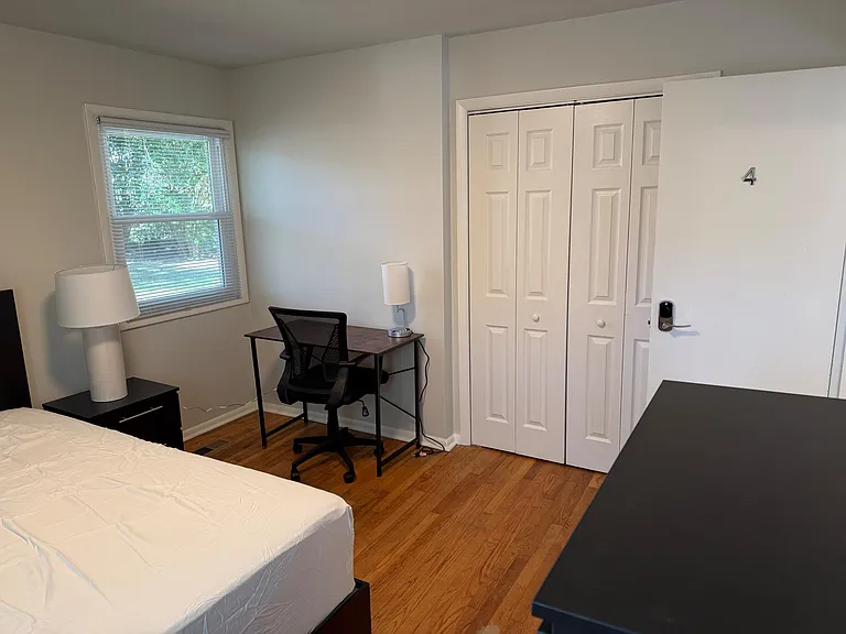 Private bedroom with hardwood floors, a large window, and a dedicated desk area, plus a roomy closet for storage.