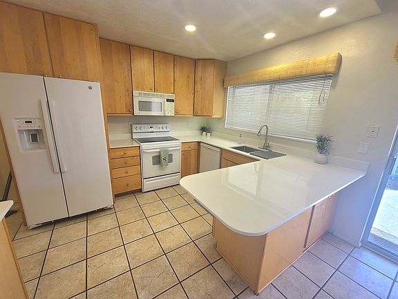 Clean white appliances and counter tops with deep bowl stainless sink and pull out faucet