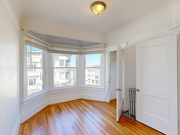 Bright bedroom with a large window, wood-like floor and a closet