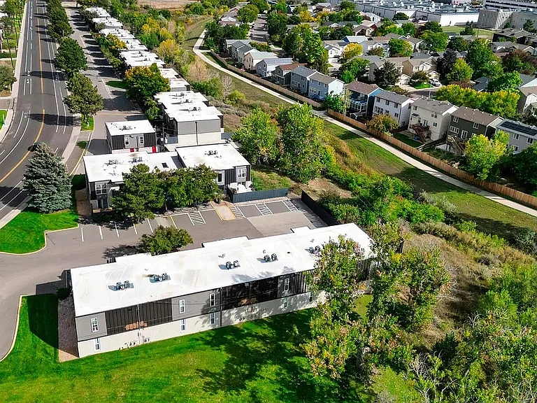 Aerial view of a charming residential community surrounded by lush greenery and well-maintained roads, ideal for a tranquil lifestyle.