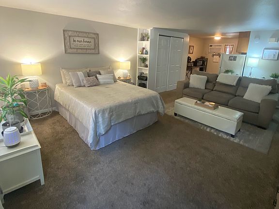 Spacious room, large picture window, bookshelf, closet space and carpet.