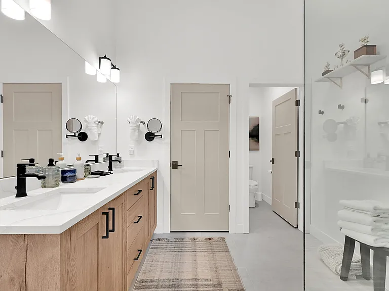 Master bathroom with large walk in shower, his and hers sinks, separate toilet room, and second stacked washer and dryer.
