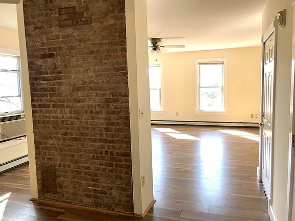 Looking toward Living room from kitchen area. Exposed brick partial wall separates living room from kitchen.