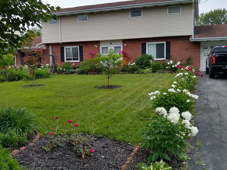 Full house exterior. Picture showcasing flower garden in front lawn.