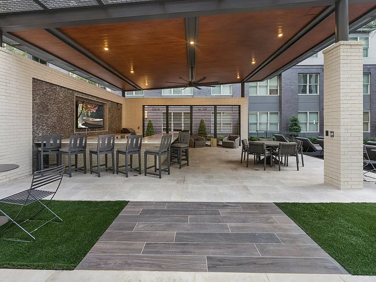 Covered poolside veranda with outdoor kitchen, bar, and television