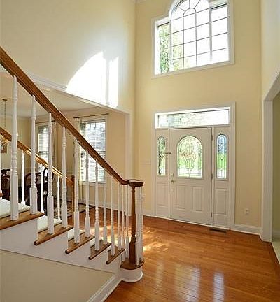 The stunning, welcoming two story foyer features a transom window above the front door and a beautiful arched window, both invit