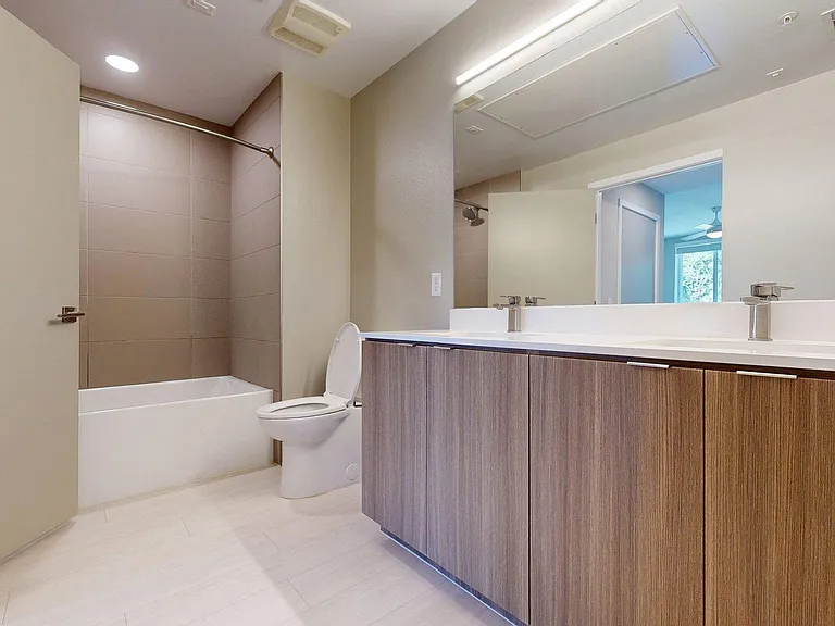 Apartment Bathroom with large soaking tub, vanity mirror and Wood-Style Flooring.