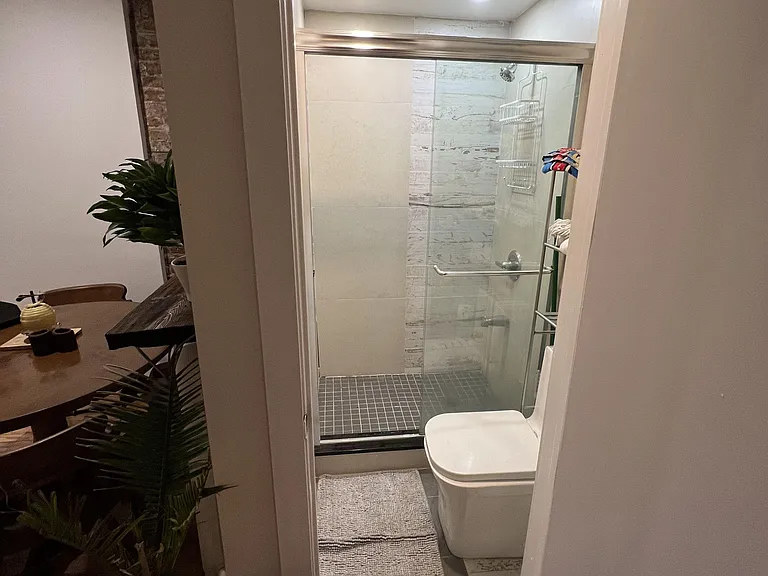Updated bathroom with a glass-enclosed shower, tiled surround, and overhead lighting for everyday convenience.