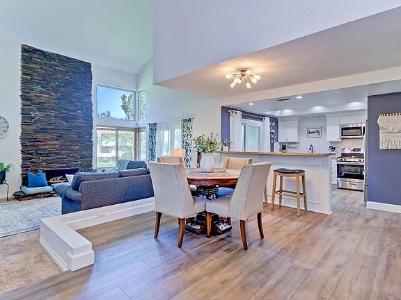 Open floorplan with custom fireplace, dining area, extended kitchen counter for eating and luxury vinyl flooring.