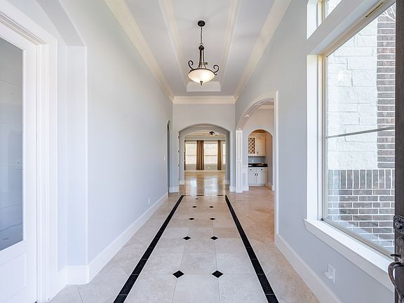 Step through elegant French doors into a bright foyer featuring high ceilings, marble flooring, and views straight through to the open-concept living area.
