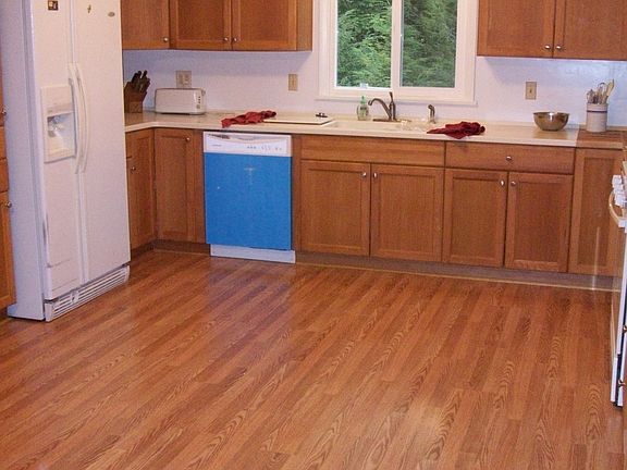 New cabinets, appliances, and flooring in large kitchen with eat-in area.